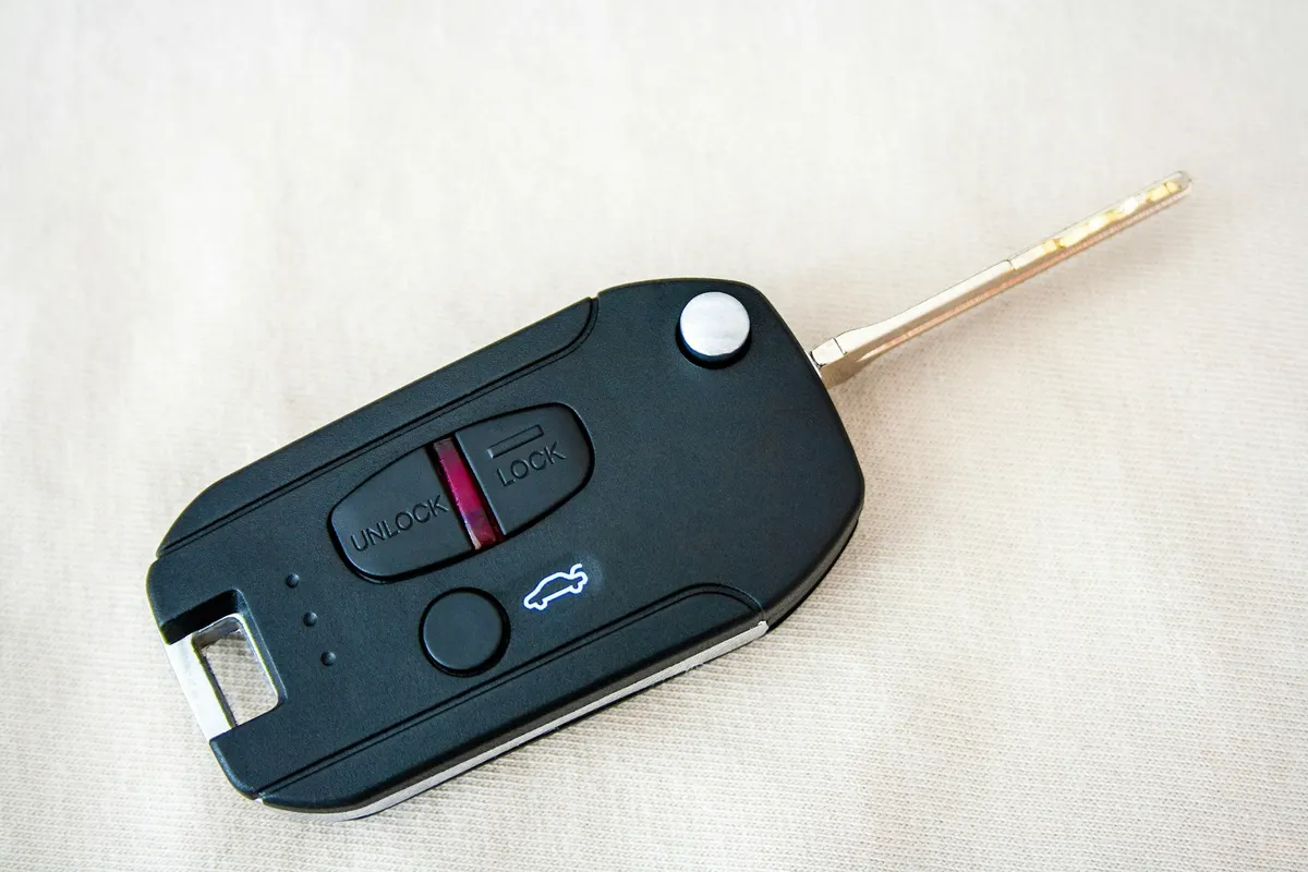 A flip key with lock, unlock and trunk buttons on a white cloth
